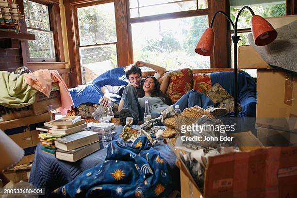 young couple relaxing in living with moving boxes - messy boyfriend stock pictures, royalty-free photos & images