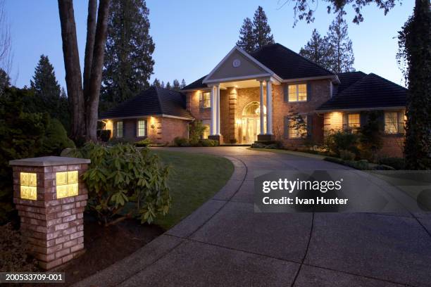 exterior of house and driveway illuminated at dusk - camino de entrada fotografías e imágenes de stock