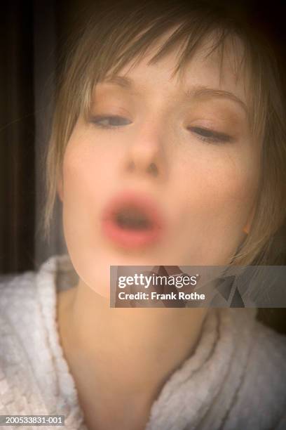 young woman breathing on glass, close-up - exhaling stock pictures, royalty-free photos & images