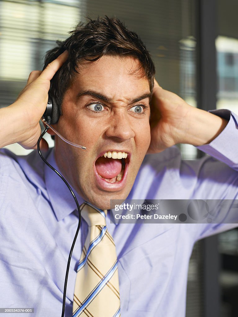 Businessman wearing telephone headset, shouting, close-up