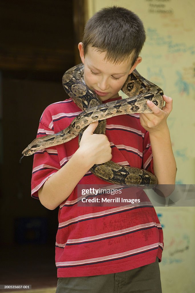 Boy (7-9) with boa constrictor around neck