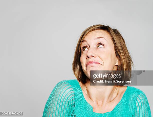young woman looking up, shrugging shoulders - shrug shoulders stockfoto's en -beelden