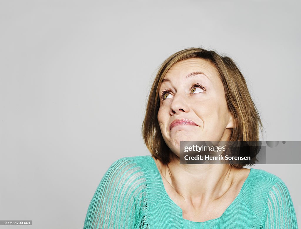 Young woman looking up, shrugging shoulders