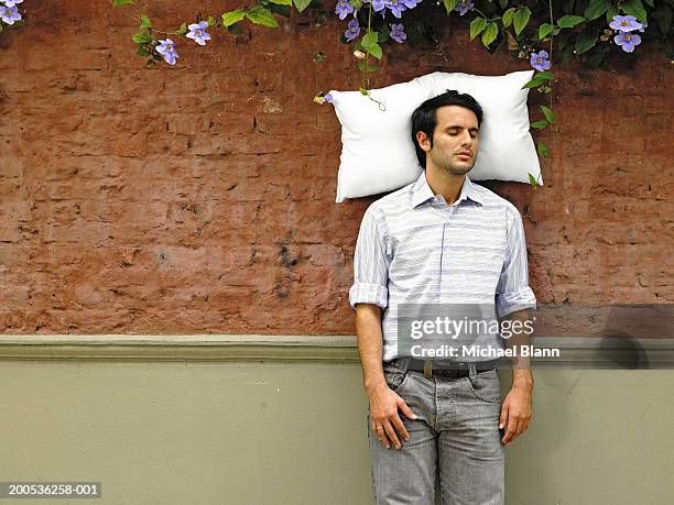 young man sleeping with pillow against wall - pillow stock pictures, royalty-free photos & images