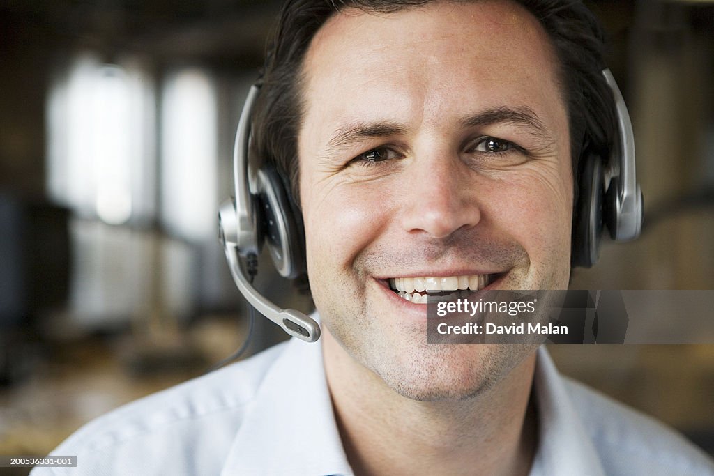 Man wearing headset in office, smiling, close-up, portrait