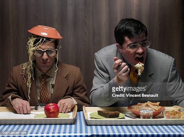office worker with bowl of pasta on head next to colleague in canteen - head on table stock-fotos und bilder