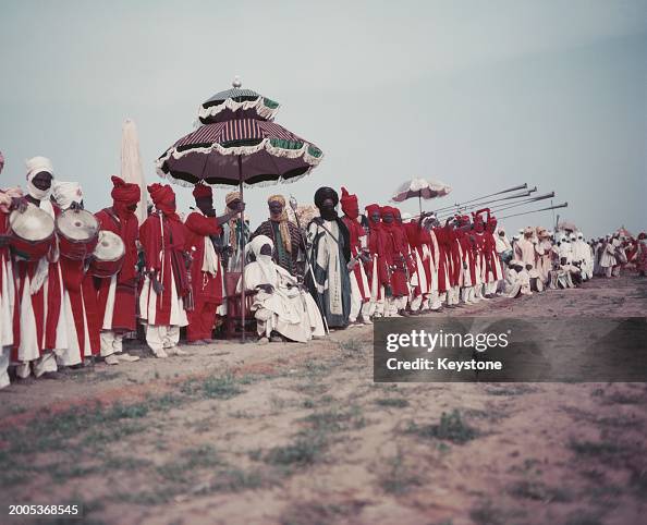 Hausa men clad in bright tunics play their traditional instruments to ...