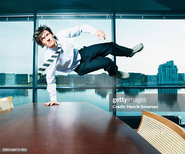businessman leaping over meeting table - camisa y corbata fotografías e imágenes de stock