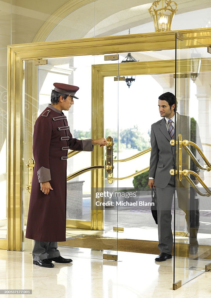 Concierge holding door open for businessman