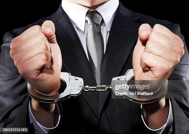 businessman hand cuffed (mid section) - handcuffs imagens e fotografias de stock