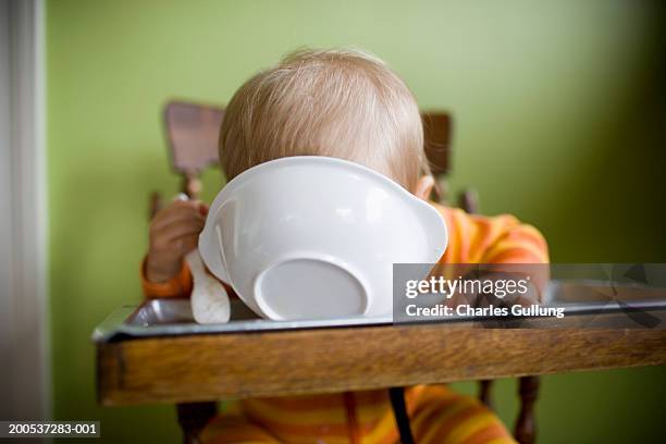 baby boy (15-18 months) in high chair, face down in bowl of food - high chair stock pictures, royalty-free photos & images