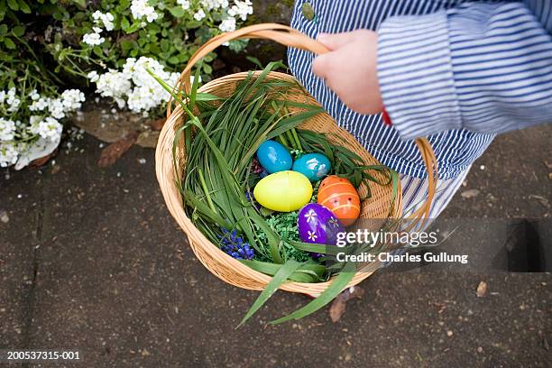 baby boy (12-15 months) carrying basket of easter eggs, low section - pascua fotografías e imágenes de stock