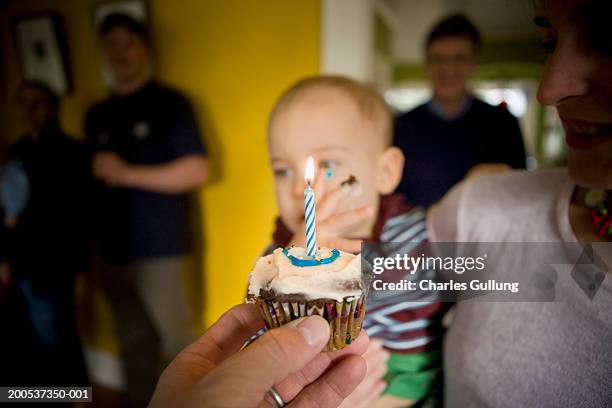 parents offering son (12-15 months) cupcake on first birthday - number 1 photos et images de collection