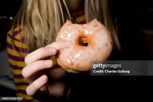 teenage girl (16-18) holding glazed donut, mid section - buñuelo en forma de rosca fotografías e imágenes de stock