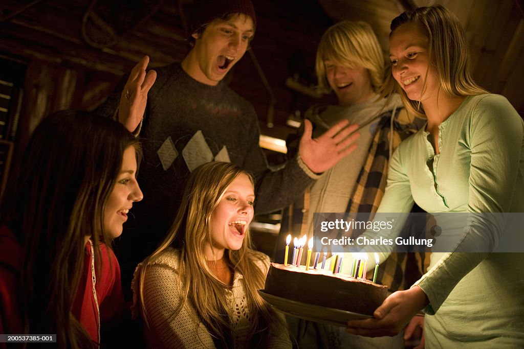 Teenagers (15-18) celebrating birthday with cake and candles