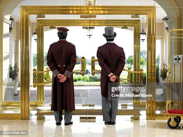 concierge and bellboy standing at hotel entrance, rear view - bellhop foto e immagini stock