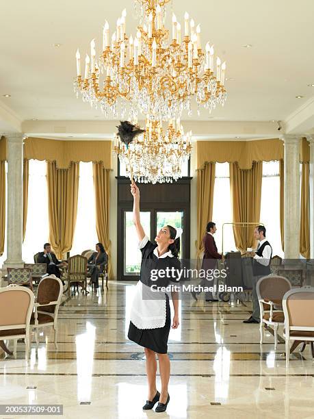 maid dusting chandelier in hotel foyer - cleaner man uniform stock pictures, royalty-free photos & images