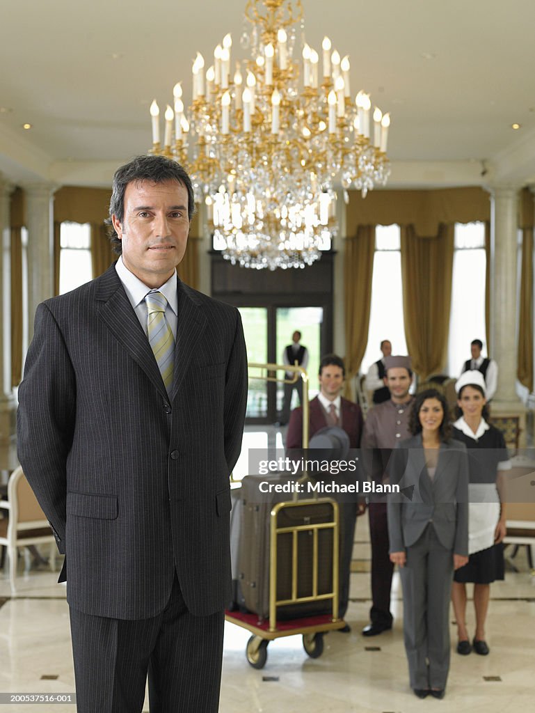 Männliche hotel manager stehen im foyer, Team im Hintergrund, portr