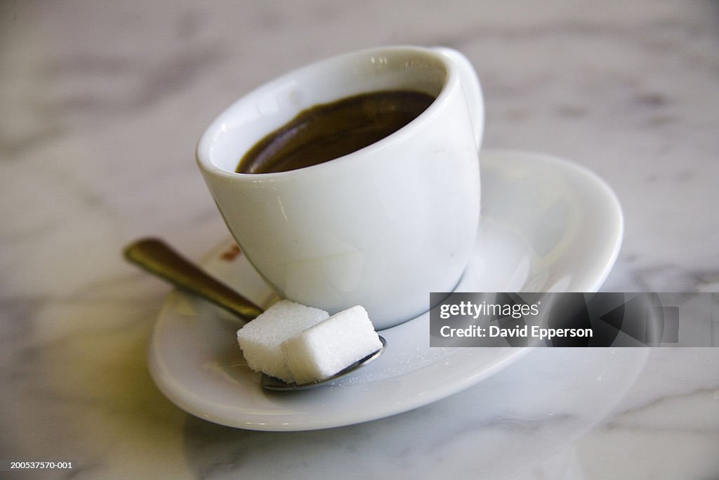Cup of coffee on marble table, with sugar cubes, close-up
