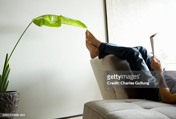mature man reading magazine on sofa, low section, side view - feet up stock pictures, royalty-free photos & images