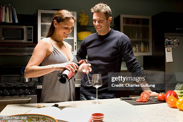 man and woman preparing food and drinking wine in domestic kitchen - wine enjoyment stock pictures, royalty-free photos & images