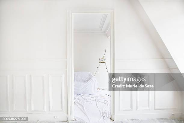 ladder by sofa covered in dust sheet in room, view through doorway - doorway stock pictures, royalty-free photos & images