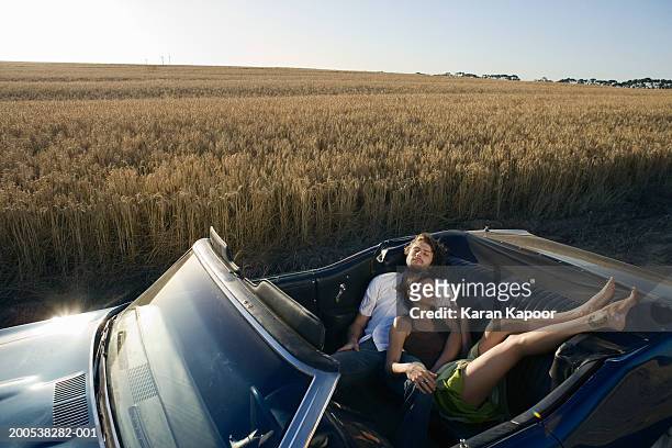 young couple sleeping in convertable car in wheat field - couple sleeping in car photos et images de collection