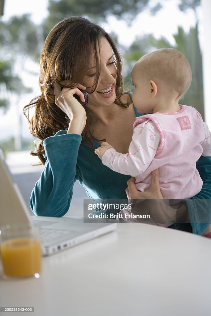Mother feeding baby daughter (12- 15 months) at table, smiling