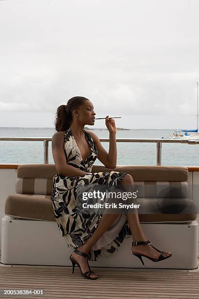 young woman on yacht smoking cigarette in cigarette holder - beautiful women smoking cigarettes stockfoto's en -beelden