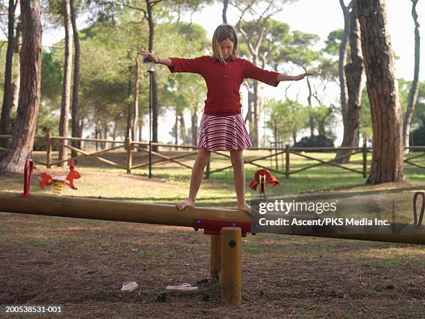 girl (10-12) balancing atop seesaw, arms outstretched - see saw fotografías e imágenes de stock