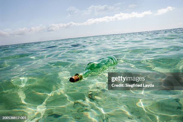 glass bottle floating in sea - flaschenpost stock-fotos und bilder