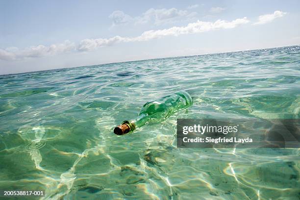 glass bottle floating in sea - message in a bottle floating in ocean stock pictures, royalty-free photos & images