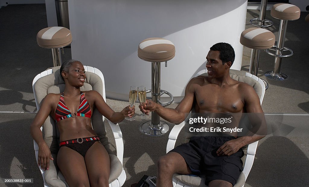 Mature couple holding  champagne on yacht, smiling at each other