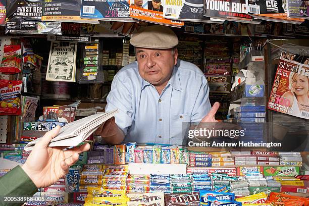 news and magazine kiosk operator offering woman newspaper - shrug shoulders stockfoto's en -beelden