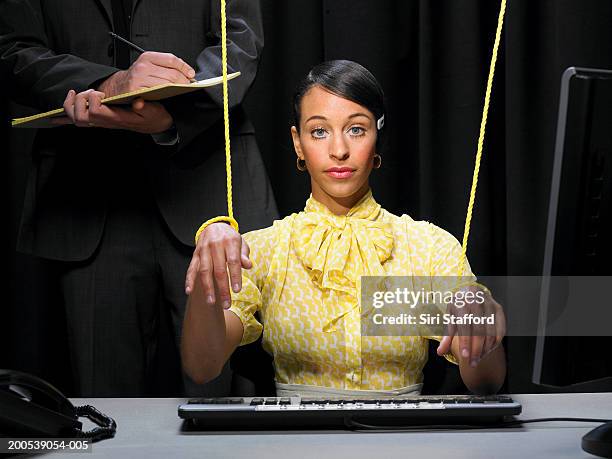 secretary with hands tied in strings, businessman in background - puppeteer - fotografias e filmes do acervo