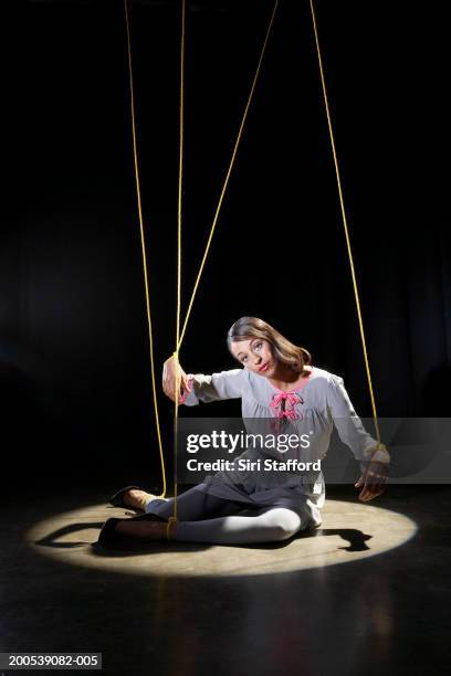 woman tied in strings sitting on floor with spotlight - puppeteer strings stock pictures, royalty-free photos & images