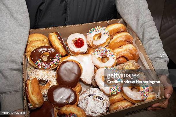 street vendor carrying box of doughnuts, mid section, elevated view - krapfen stock-fotos und bilder