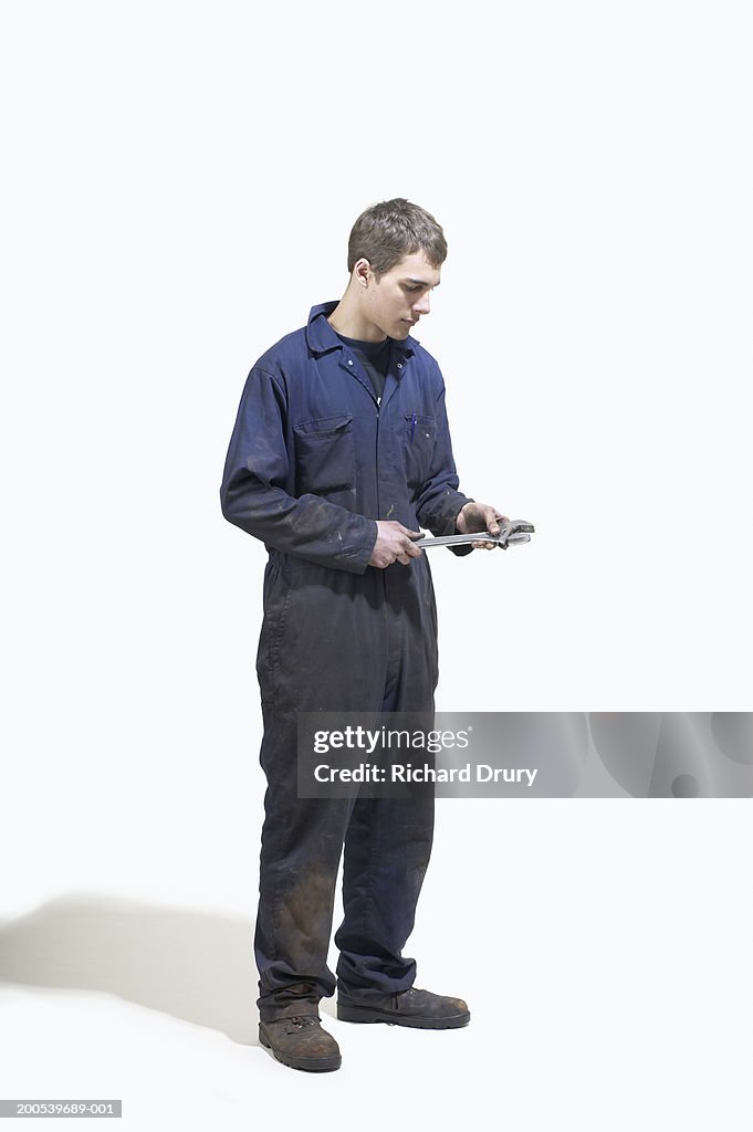 Young man wearing boiler suit holding wrench