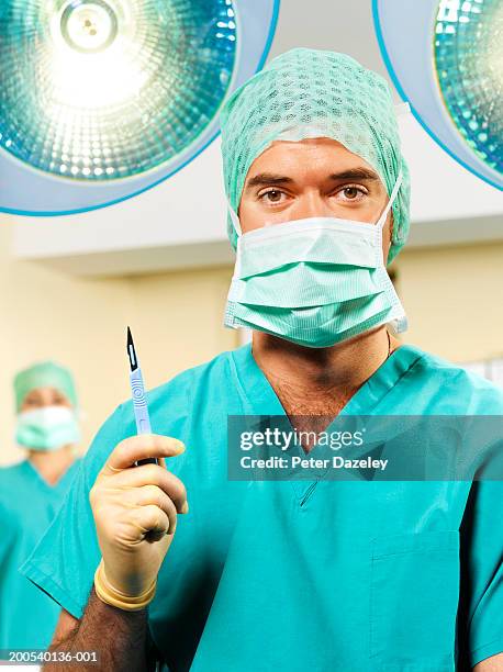 young male surgeon holding scapel, portrait - scalpel - fotografias e filmes do acervo