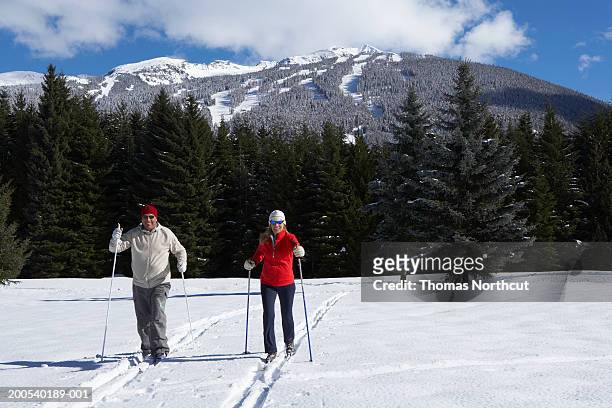 mature man and woman cross-country skiing - women's cross country skiing - fotografias e filmes do acervo