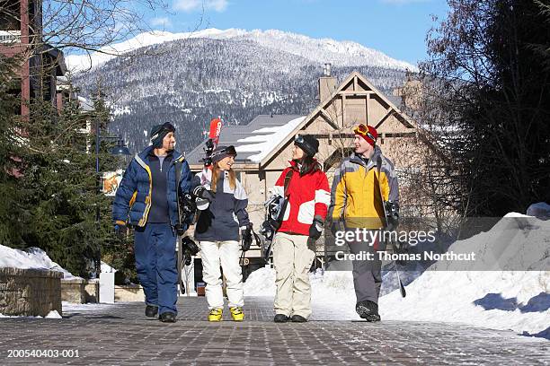 four adults with skis and snowboards walking and talking - whistler stockfoto's en -beelden