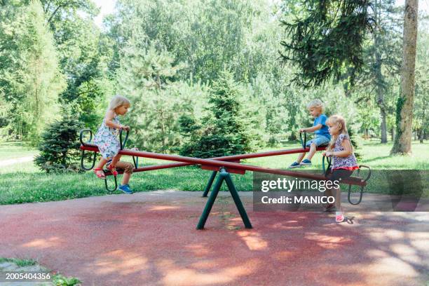 children on a seesaw - wippe stock-fotos und bilder