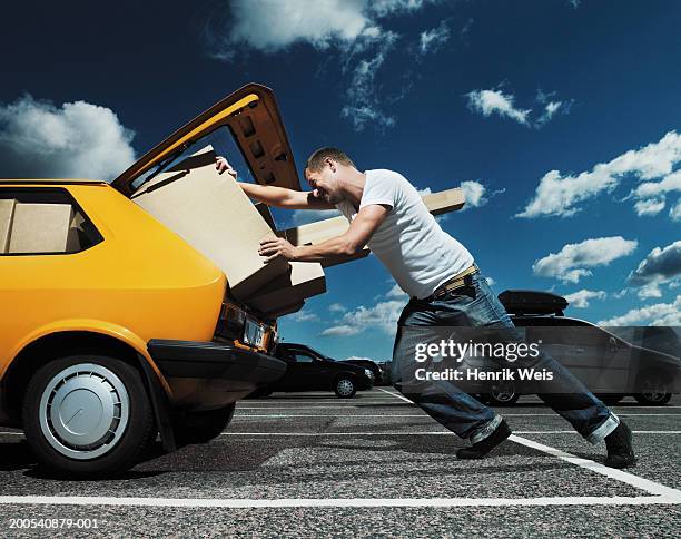 man pushing packages into open boot of car - car trunk stock pictures, royalty-free photos & images