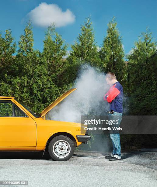 man looking at yellow car with steam pouring from bonnet - vehicle breakdown foto e immagini stock