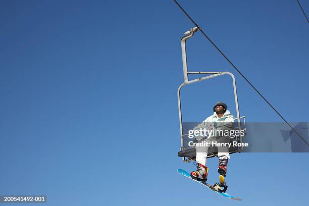 male snowboarder riding chair lift - ski lift stock pictures, royalty-free photos & images