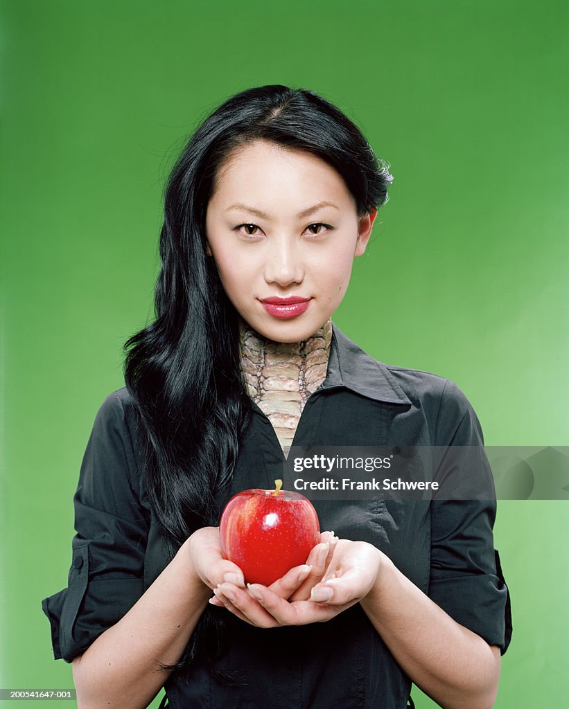 Young woman with snakeskin neck and eyes offering apple