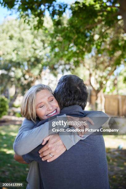 mature woman smiling and hugging her husband outside in summer - financial freedom stock pictures, royalty-free photos & images