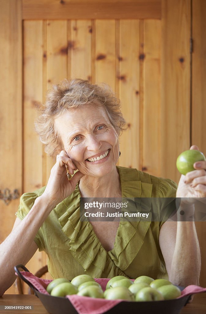 Senior woman with bowl of apples, smiling, portrait