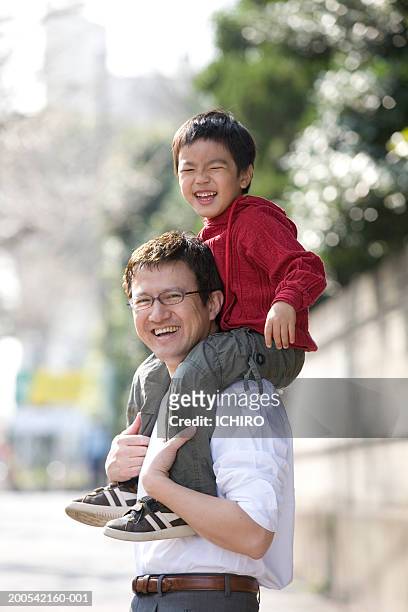 father carrying son (4-6) on shoulders, smiling, side view - asian smiling father son stock pictures, royalty-free photos & images