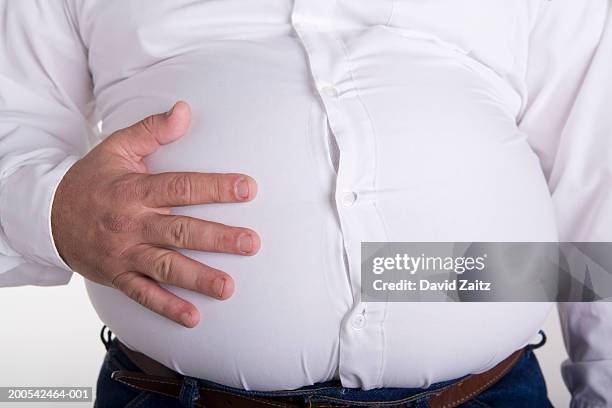 man with hand on enlarged stomach, mid section, close-up - distorted body image stock pictures, royalty-free photos & images